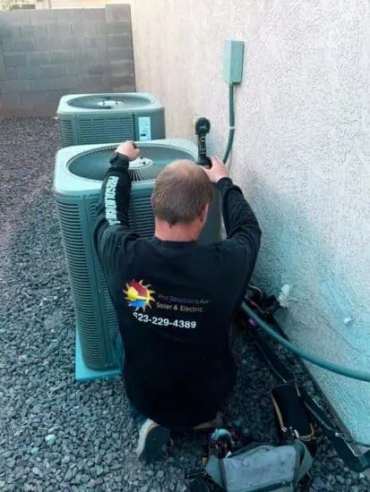 A Pro Solutions Air technician servicing two outdoor condenser units